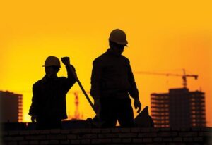 Construction workers at building site during sunset